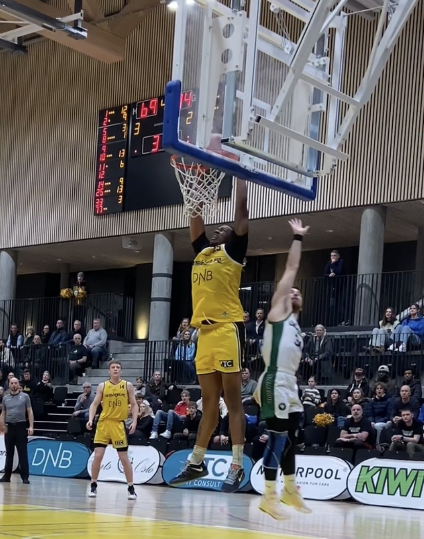 Basketballspiller hopper opp og er i ferd med å score i kamp inne i Leikvollhallen - Klikk for stort bilde