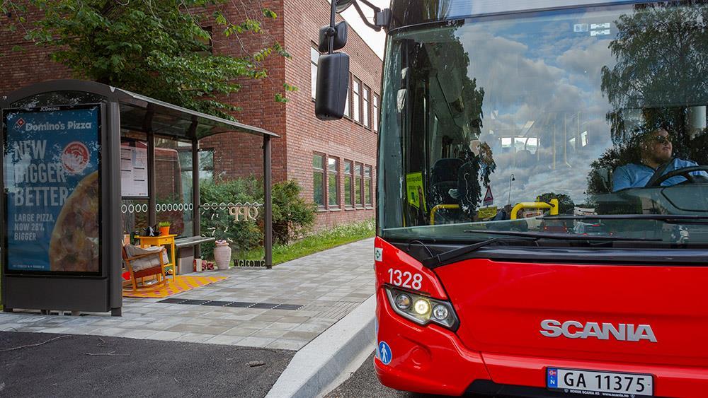 Rød buss ved bussholdeplass - Klikk for stort bilde