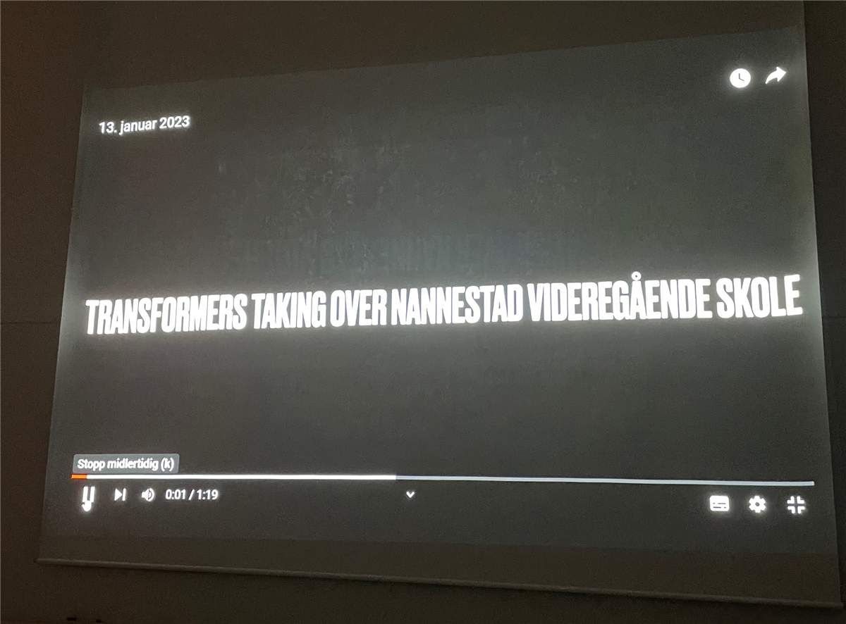 Bildet viser en storskjerm hvor tittelen "Transformers taking over Nannestad videregående skole". - Klikk for stort bilde