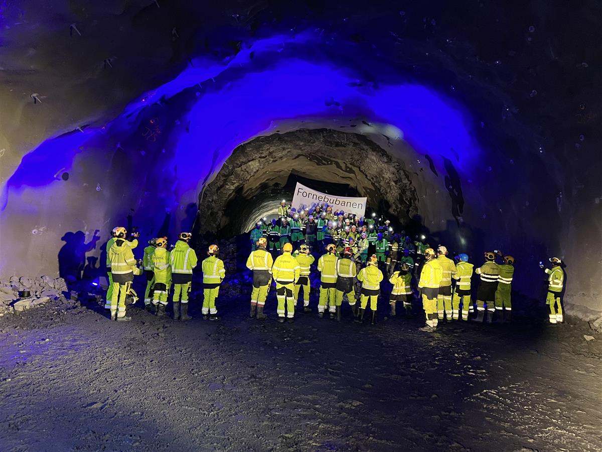 Gruppe mennesker inne i en nysprengt tunnel. Alle i gule vernedresser - Klikk for stort bilde