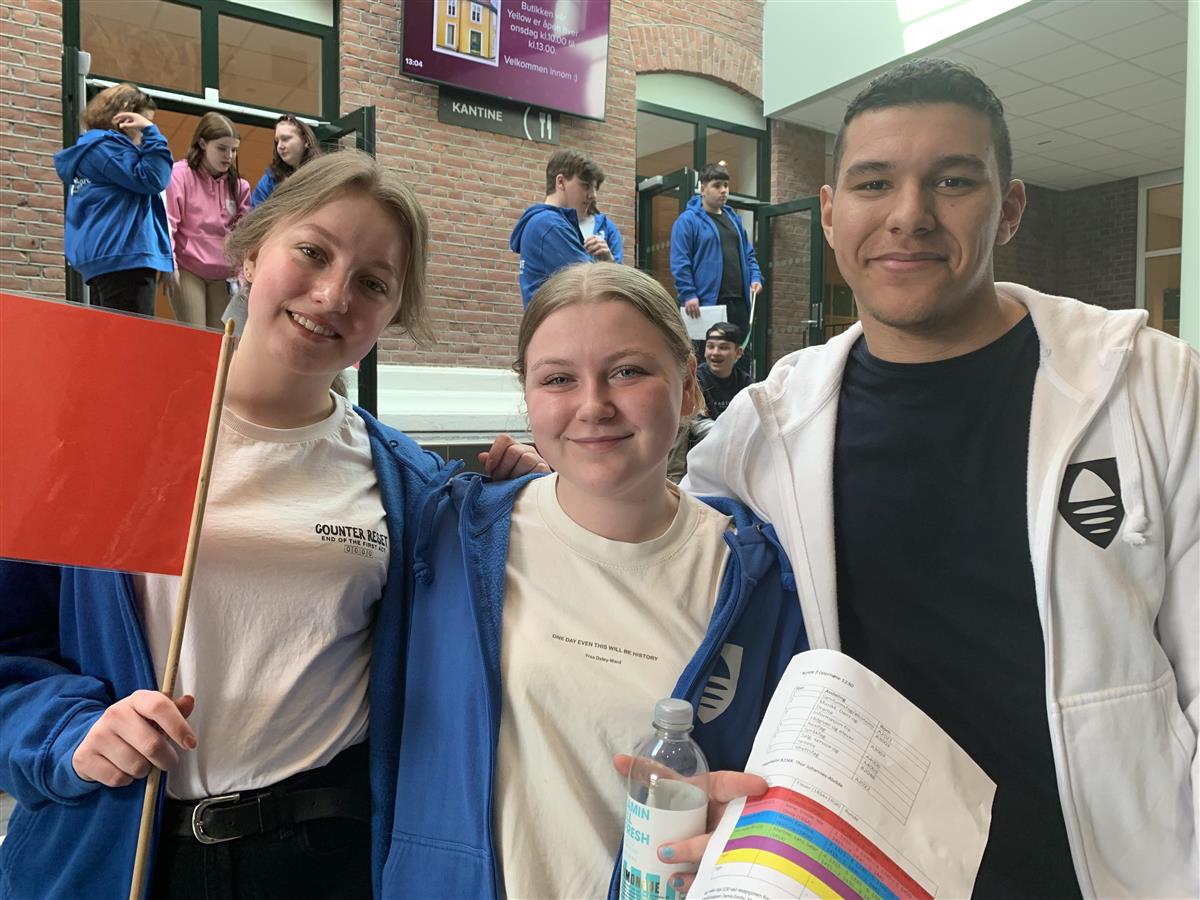 Tre elever som står med guideflagg - Klikk for stort bilde