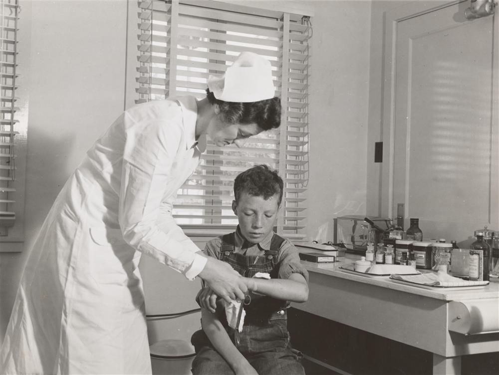 Svart hvitt bilde av sykepleier som pleier en gutt - Klikk for stort bilde