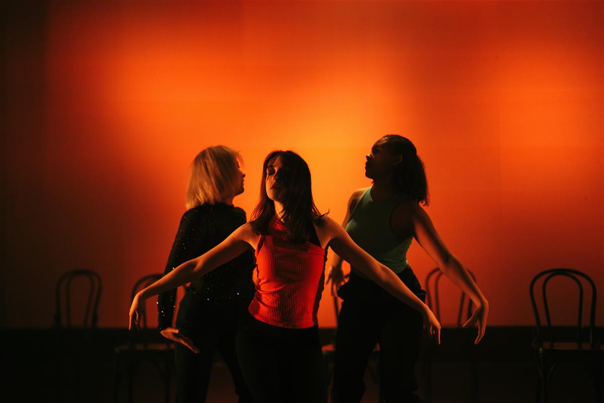 Tre danseelever i rødgult lys - Klikk for stort bilde