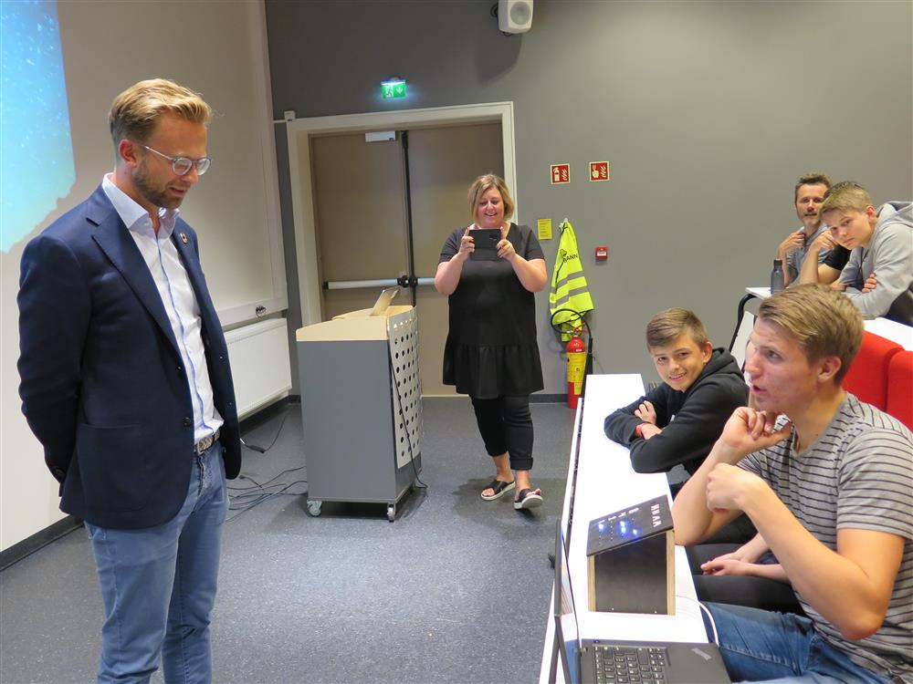 Digitaliseringsminister Nikolai Astrup som ser på at en elev styrer en robot - Klikk for stort bilde