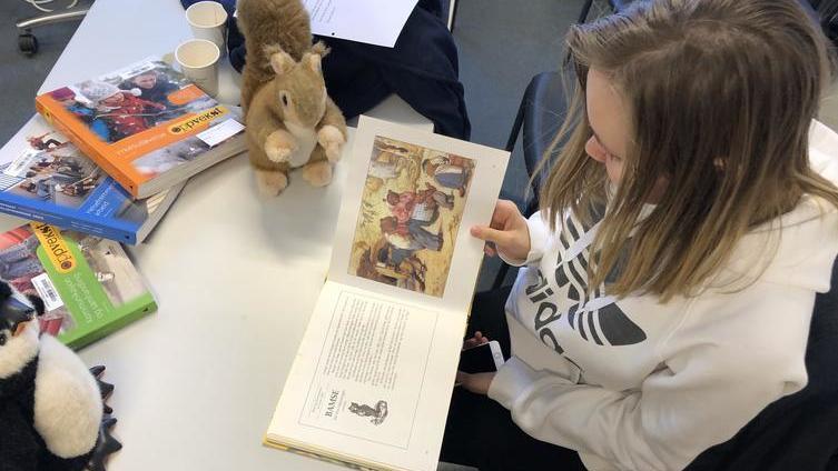 Bildet viser en elev som leser fra en bok for barn. - Klikk for stort bilde