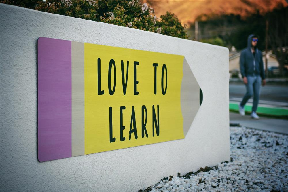 Skilt formet som blyant på vegg med påskriften &quot;Love to learn&quot; - Klikk for stort bilde