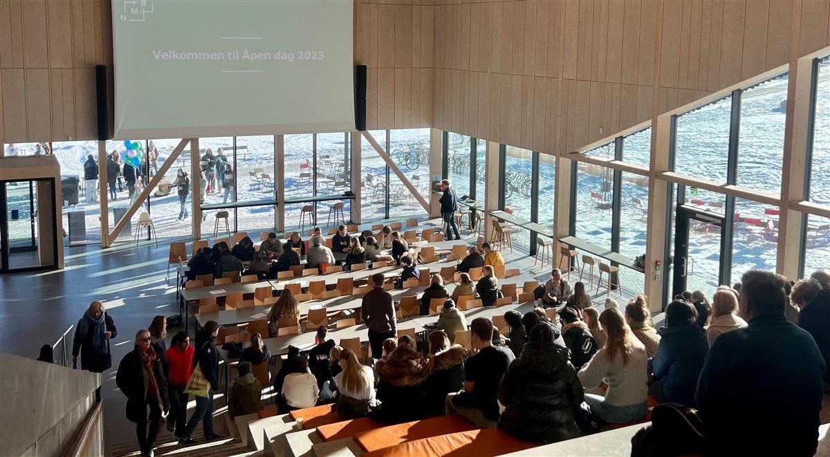 Elever besøker universitetet i Ås. Elevene sitter på benkerader i et auditorium med foreleser og prosjektorskjerm foran seg. - Klikk for stort bilde